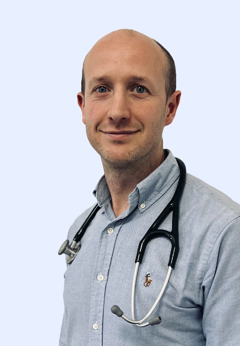 Dr Jack Ogden smiling on a blue background