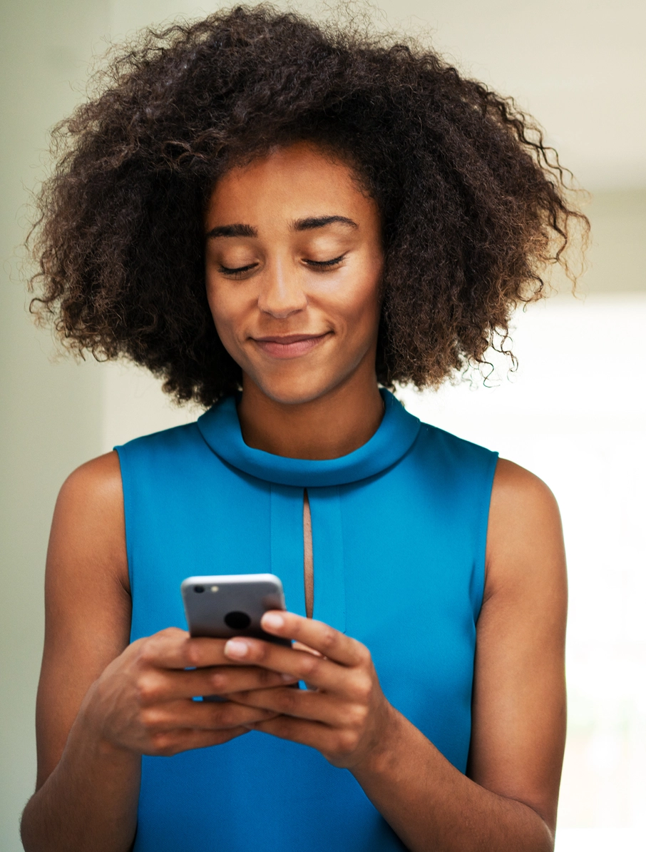 Young black woman smiling and using smartphone