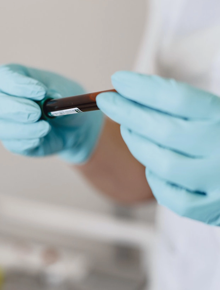 A doctor wearing gloves and holding a vial of blood