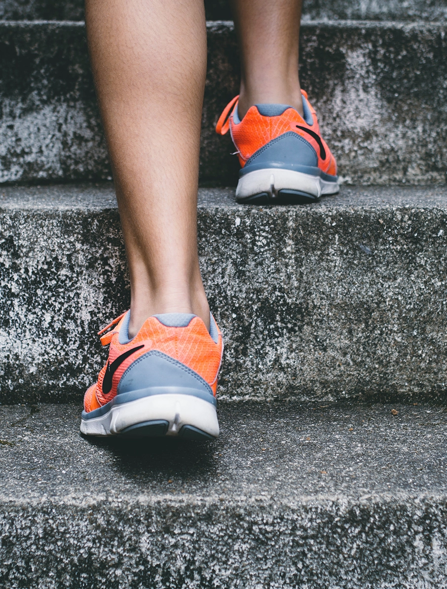 A close-up of a woman in running shoes climbing steps